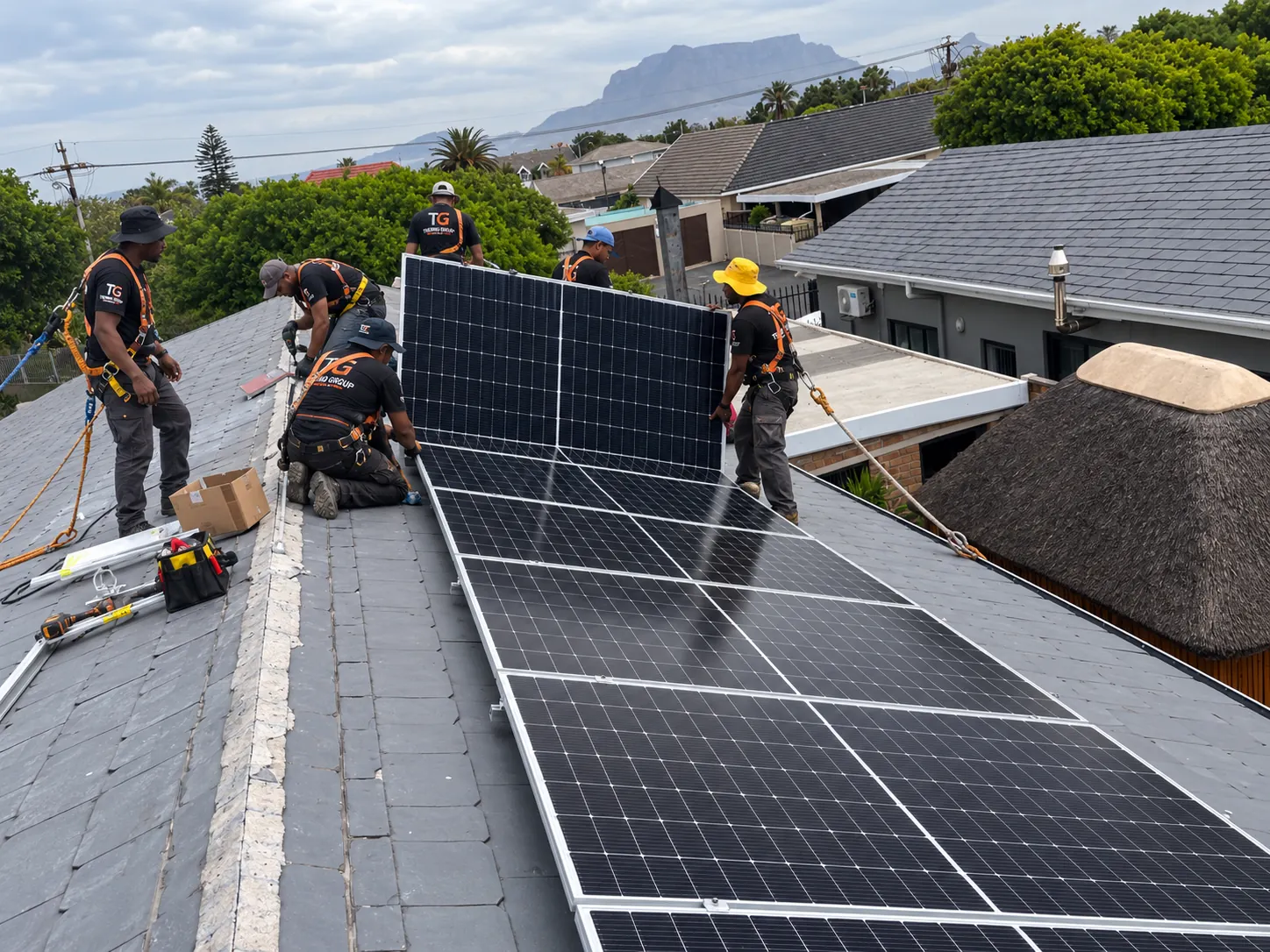 Thermo Group solar installation team fitting panels on a roof in Blouberg with Table Mountain in the background
